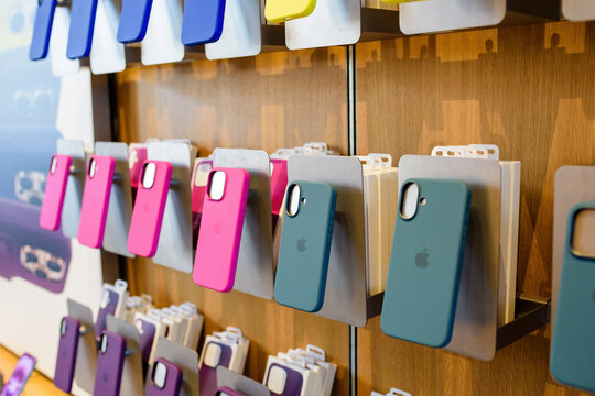 Paris, France - Sep 20, 2024: Fuchsia and green iPhone 16 Pro and 16 Plus cases displayed on stands inside Apple Store, showcasing latest phone protection
