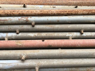 Rusty old metal pipes lie in a row. Scrap metal. Metal background