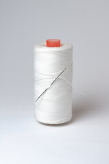 One single thread spool with needle on white background