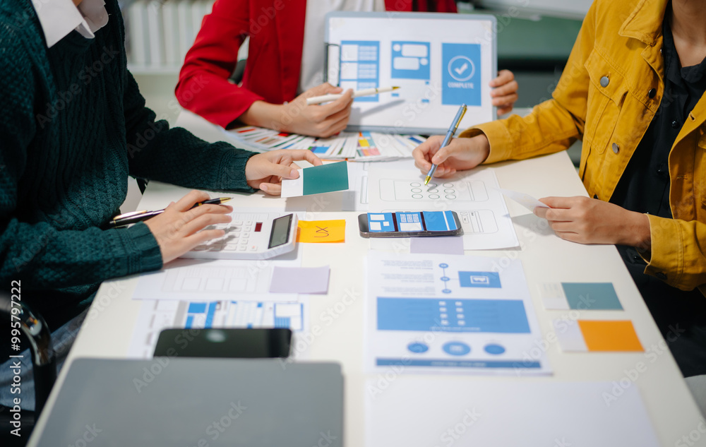 Wall mural close up view of ui developer team brainstorming on their project with laptop, smartphone and digita