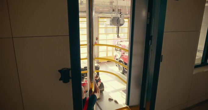 Firefighters Using the Pole to Slide Down From the Second Floor of the Station, Rushing to Respond to an Emergency Call. Scene Captures the Urgency of the Fire Department. Warm Slow Motion Footage