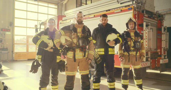 Diverse Team of Firefighters Stands Confidently in Front of a Fire Truck in a Fire Department, Looking at Camera and Showing Their Unity. First Responders Ready to Protect the Community