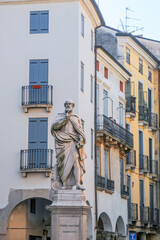 Statue of renowned architect Andrea Palladio in front of colorful buildings with traditional Italian architecture in Vicenza, Italy. Balconies and shuttered windows adorn the facades