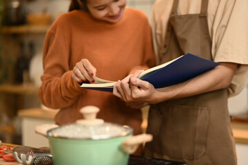 Young couple looking at a recipe book, enjoying the process of cooking together in the kitchen