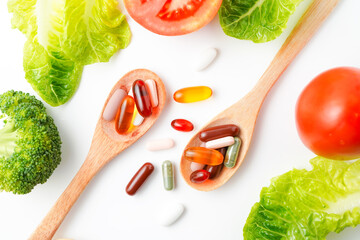 Pills and capsules in wooden spoon with fresh vegetables, Multivitamins and supplement