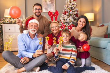 Family holding balloons shaped as numbers 2025 while celebrating New Year at home