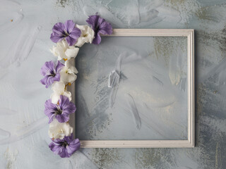 A white frame with purple and white flowers on a textured blue background