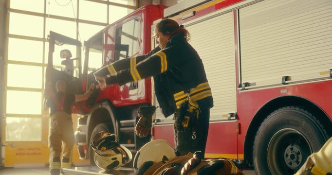 Team of Firefighters, Including a Young Female Crew Member, Rush to the Garage as the Alarm Sounds. They Gear Up Quickly, Climb Into the Fire Truck, and Head Off to Respond to an Emergency. Warm Color