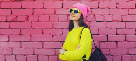 Stylish young teenager girl posing in vivid yellow colorful clothes on pink brick wall background