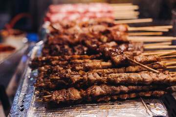 Korean barbecue, Ddakkochi, grilled chicken and pork skewers, variety of different traditional street food selection in Seoul, South Korea, night market with local vendor stalls cooking tasty dishes