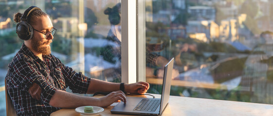 A young man works on a laptop. Remote work using a laptop.