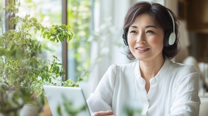 A woman wearing headphones and smiling while looking at a tablet