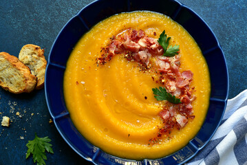 Autumn pumpkin soup with smoked bacon. Top view with copy space.