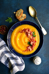 Autumn pumpkin soup with smoked bacon. Top view with copy space.