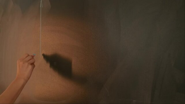 Close up of woman hand drawing coordinate axis with parabola on chalkboard, professor writes on blackboard or student solving task. Education and science concept.