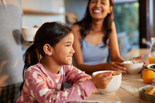 Little hispanic girl enjoying breakfast with milk and cereal