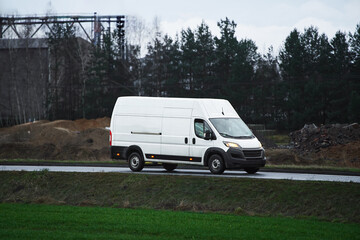 Van traveling through rural landscape with factory
