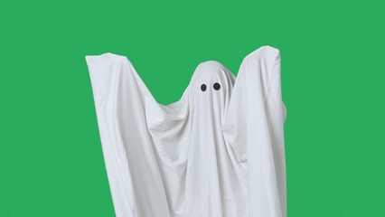 Funny halloween ghost in white sheet isolated on chroma key green screen background shows scary moves. Happy halloween spooky concept.