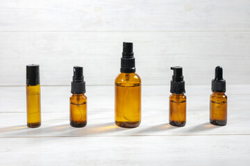 Amber bottles with facial liquid and a linen towel on wooden table
