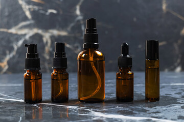 Amber bottles with facial cosmetics on the dark background