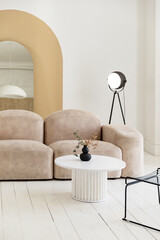 Interior of bright room with sofa, floor lamp, mirror and coffee table.