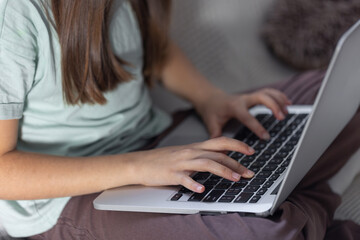 The girl is typing on the laptop keyboard. Girl's hands on the keyboard.