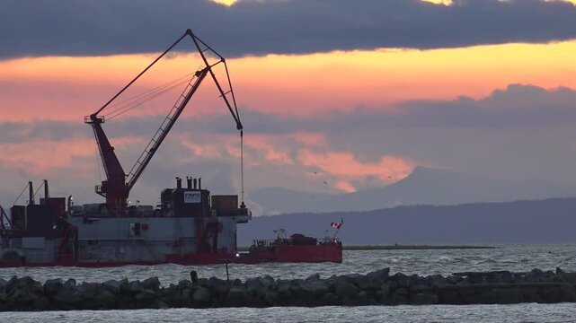 A dredger sails past Steveston Harbor during sunset, British Columbia, Canada
