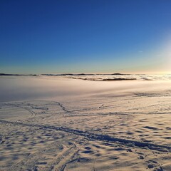 The concept of relaxing in the mountains in winter in the snow on skis, snowboards or sleds, walking under the setting sun at sunset on the Wasserkuppe mountain in Hesse Germany