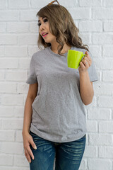 Portrait of a young Asian teenage woman wearing a T-shirt and jeans, posing in a brightly lit room with white brick walls