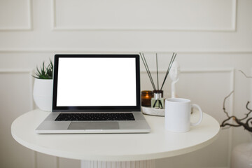 Fototapeta premium Laptop and white mug with tea on a table. Workspace in a modern room.