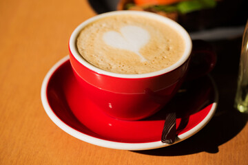 A red coffee cup with with cappuccino