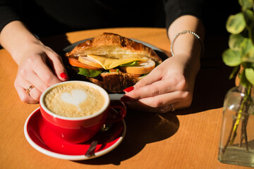 A woman is holding a croissant and a cup of coffee
