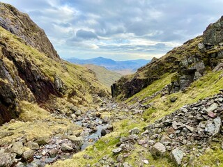  Rocky mountain pass with a small stream flowing through, surrounded by dramatic peaks