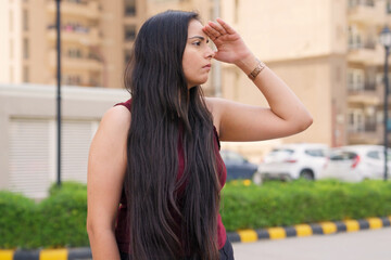 Indian Woman Looking Around With Hand On Forehead