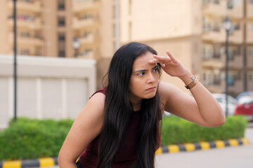 Indian Woman Looking for Someone With Hand On Forehead