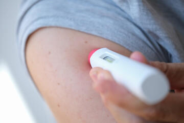 back close up of an anonymous person injecting himself a treatment such as insulin or Adalimumab, Etanercept or epinephrine into his shoulder. It is a white pen injector with red head for health care © LaMorenita