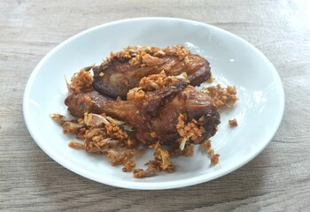deep fried chicken tight and legwith pepper dressing crispy fried garlic on plate
