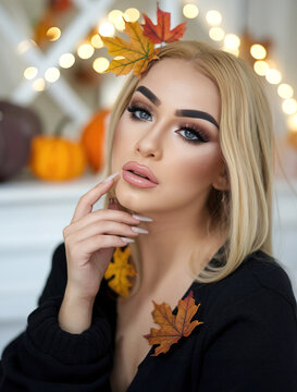 Portrait einer sch&ouml;nen blonden Frau mit perfektem Permanent Make-Up und Gel-Fingern&auml;geln mit herbstlichen Bl&auml;ttern