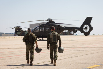 Dos pilotos militares de helicopteros se dirigen hacia sus helicopteros.
