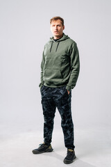 Fototapeta premium Man in green hoodie, camo pants indoors.