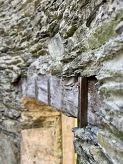 A close-up of a weathered stone doorway with wooden beam embedded, highlighting the rugged textures and aged craftsmanship. The scene conveys a sense of history and timeless architecture.