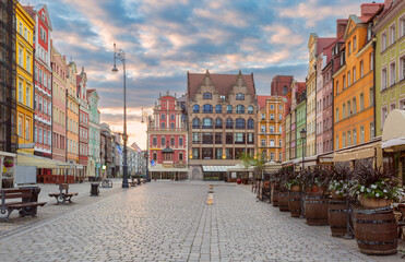Morning view of colorful buildings on Rynek Square in Wroclaw, Poland, with street lamps and a partly cloudy sky