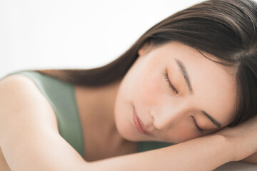 Obraz premium Portrait of a young beautiful Asian woman. She has straight black hair. She is leaning on the table.