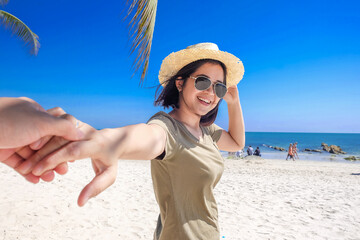 Beautiful asian women leading man hand into the sea on beach exotic sea blue sky