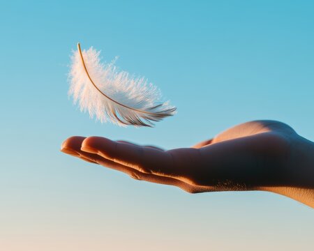 Fototapeta A delicate feather floating above an open hand against a serene, blue sky, symbolizing lightness and freedom.