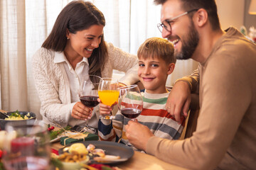 Parents making a toast with son while having Christmas dinner