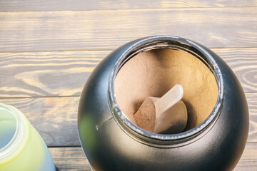Mass gainer protein powder for muscle gain in black container. Healthy sports nutrition. Close up spoon for right dose.