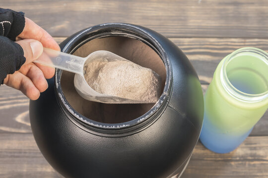 Mass gainer protein powder for muscle gain in black container. Healthy sports nutrition. Close up spoon for right dose.