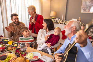Family celebrating Christmas singing songs and playing the guitar at home