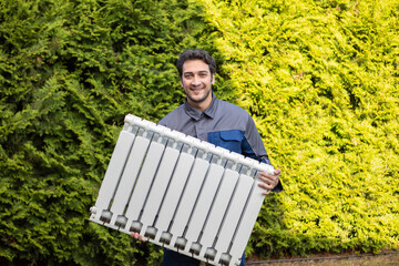 The handyman holds the radiator. Preparation for the harsh winter	